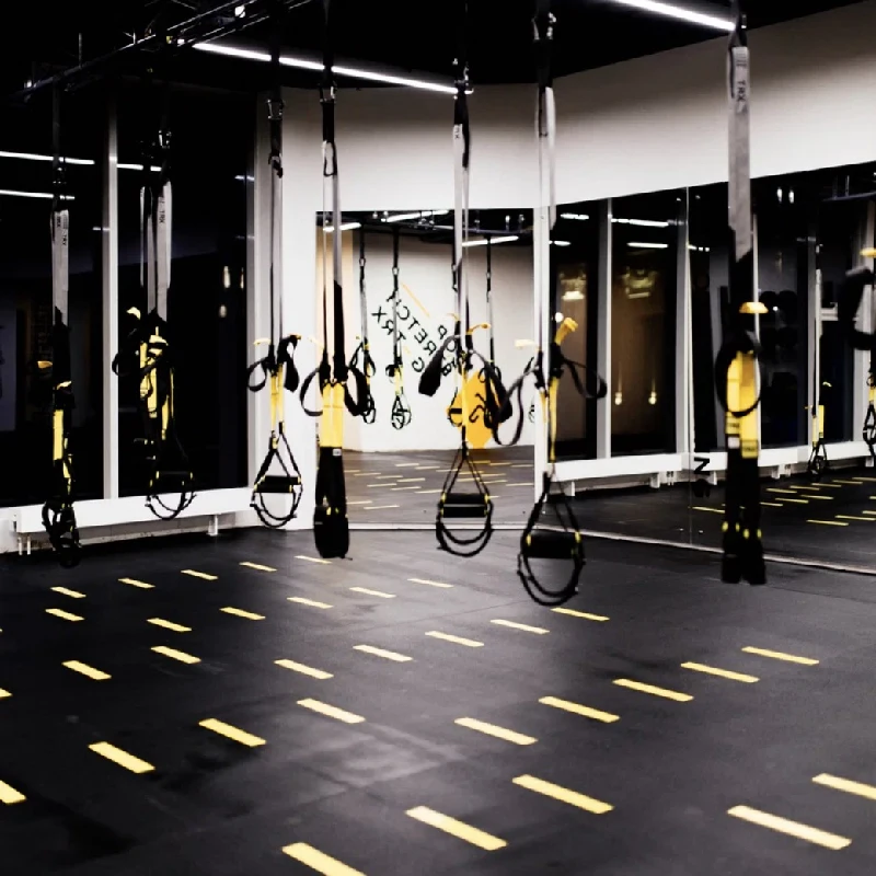 Black rubber gym flooring with yellow dashed functional agility markings.