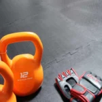 Kettlebell and gym gloves on black interlocking floor