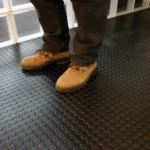 Person in boots walking on black coin-pattern floor