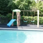 Playground set on black rubber safety tiles by a pool