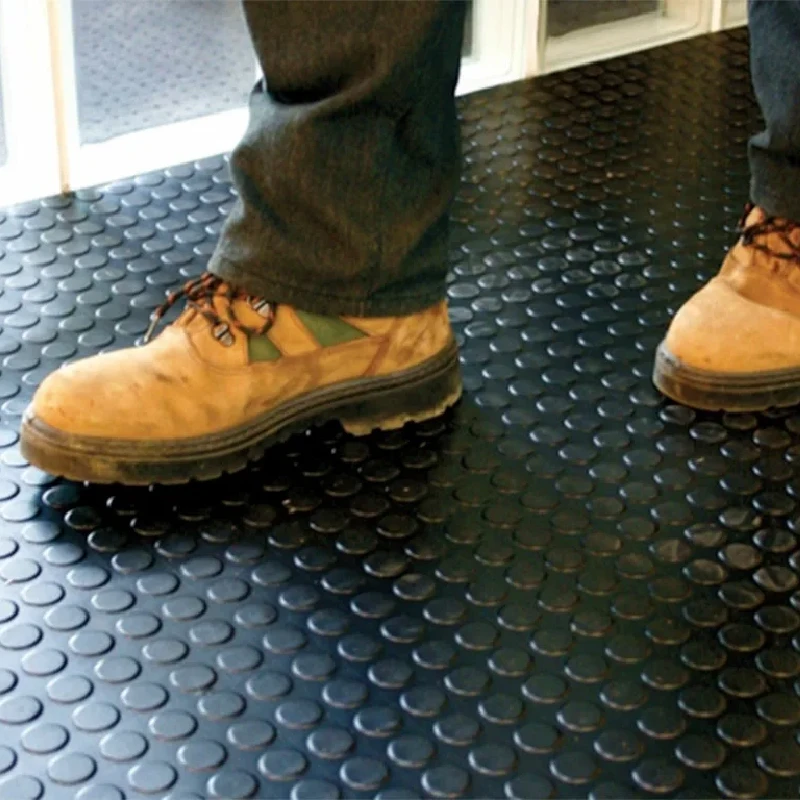 Textured black rubber flooring with a raised coin-top traction pattern.