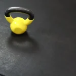 Yellow kettlebell on a textured black gym mat